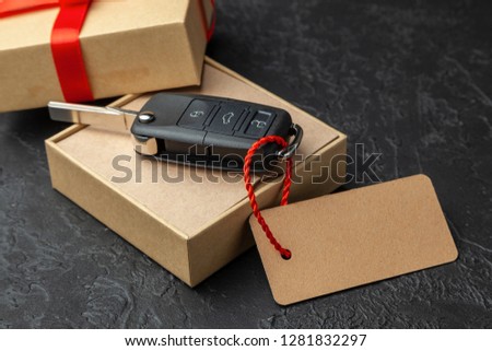 Gift box with car keys with remote control alarm system with red ribbon bow and label