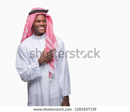 Young arabic african man wearing traditional keffiyeh over isolated background cheerful with a smile of face pointing with hand and finger up to the side with happy and natural expression on face