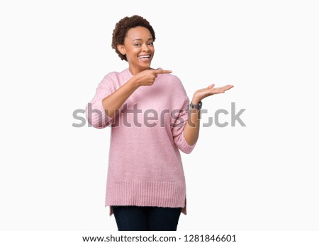 Beautiful young african american woman over isolated background amazed and smiling to the camera while presenting with hand and pointing with finger.