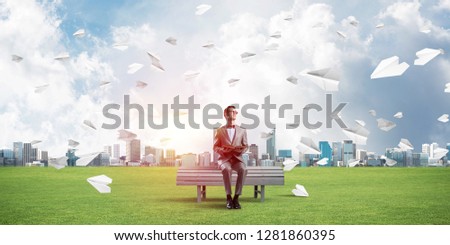 Funny man in red glasses and suit sitting on bench and reading book