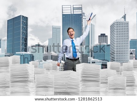 Attractive businessman keeping hand with book up while standing on pile of paper documents with cityscape on background. Mixed media.