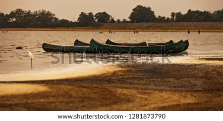 several canoes set on the shore of the lake in the early evening
