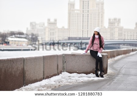 Asian girl on the river embankment in the city in winter