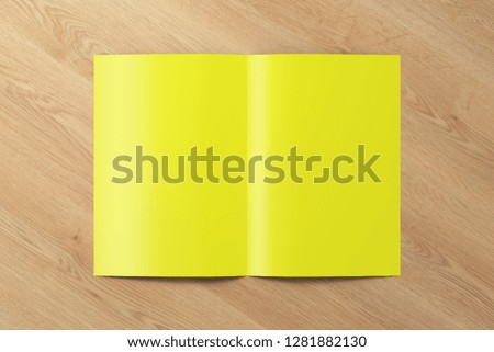 Blank yellow half-folded flyer leaflet on wooden background. With clipping path around brochure. 3d illustration