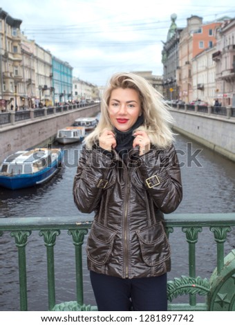 Young pretty blonde woman outdoor in the center of the Saint-Petersburg. view at Nevskiy prospektl from the Italian bridge. River and boats.