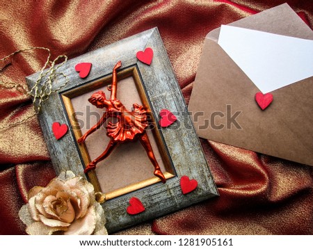 St Valentine day greeting card and an envelope with romantic symbols nearby - photo frame, the figure of a ballerina, flowers, red hearts and envelope on red background.