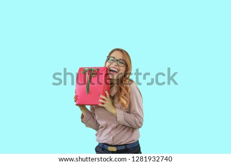 Attractive young woman holding a gift in a red box with a green ribbon cuddles and smiles, New Year's holidays, birthday, marriage proposal