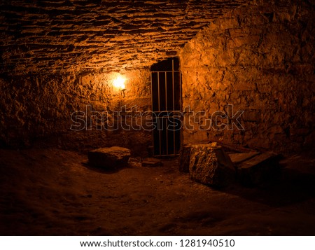 Scottish underground dungeon cells lit only by torchlight Royalty-Free Stock Photo #1281940510