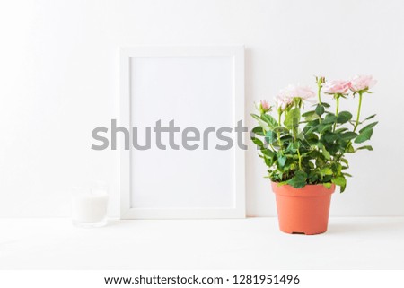 Mockup with a white frame and small pink roses in a pot on a light background