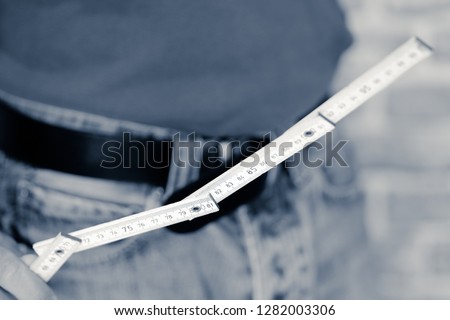Worker in blue jeans and T-shirt holds work tool in hand, monochromatic interpretation of the photographic shots.