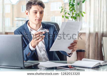 Man agent holding a car toy and documents for registration of the car in the office. The concept of buying selling and rental of transport Royalty-Free Stock Photo #1282013320