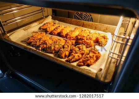 Freshly baked chicken fillet on a baking sheet in an electric oven. Cooking chicken nuggets. Series. Royalty-Free Stock Photo #1282017517