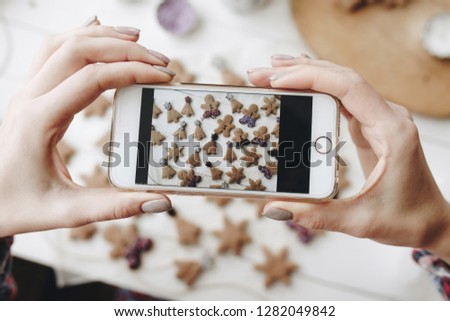 Horizontal phone in womans hands above table with sweet cookies