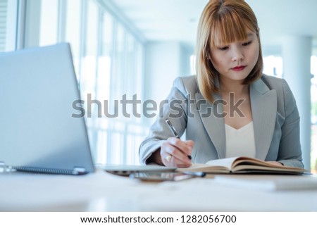 Portrait of working woman writing something on papers or signing document. This picture can be used in such concepts as business woman, financial theme, clerk, manager, office environment and so on.