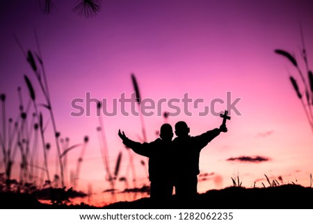 Two children holding cross and worship god with light sunset background,christian concept.