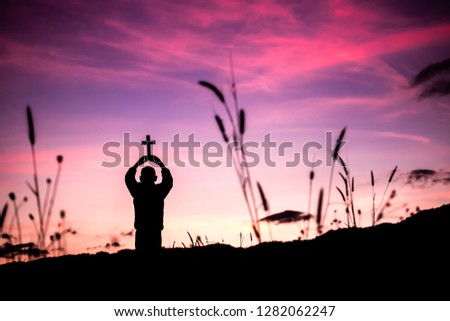 Children holding christian cross overhead with light sunset background,christian concept.
