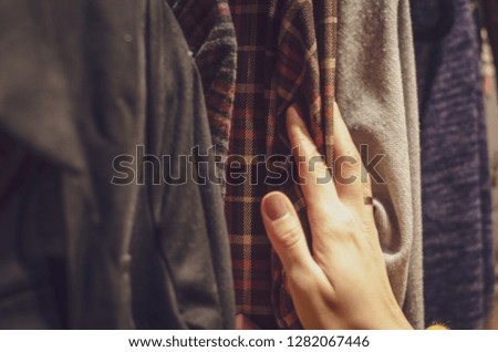 woman touches clothes. Young woman choosing clothes on a rack in a showroom