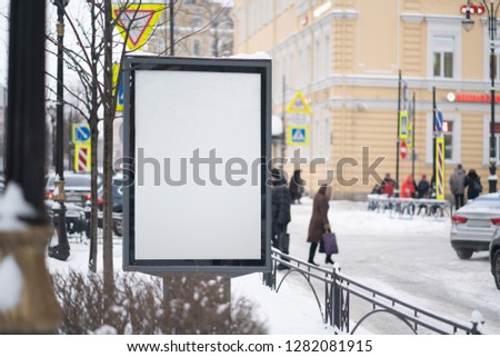 Vertical mock-up of city poster winter city with thick edges, blank white billboard in urban settings, empty street information placeholder on sidewalk with copy space for logo