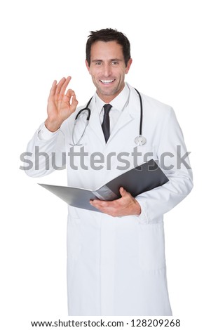 Portrait of friendly doctor making Okay gesture. Isolated on white