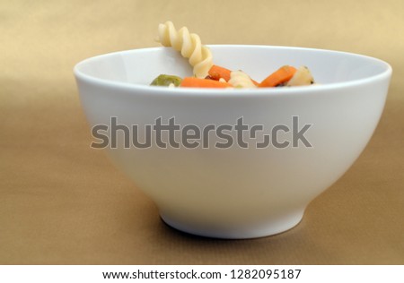 Bowl of soup with a noodle looking out 