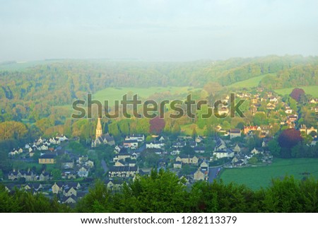 A heavy mist and an aeriel view of the Cotswold village of Woodchester with the church of St Mary in the heart of the village in spring, Gloucestershire, England, UK