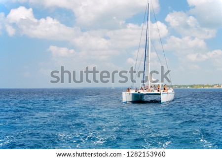 Catamaran with big white sails in a tropical sea near island with palm trees. Tour along coast. Royalty-Free Stock Photo #1282153960