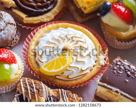 Closeup of a lemon tart with other pastry items such as cakes, tiramisu and cookie.