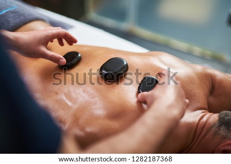 Top view close up picture of young man lying on massage table and receiving therapeutic spa procedure