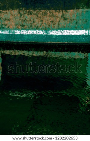 Abstraction from an image of the side of a rusty boat moored in the water of a harbour marina 
