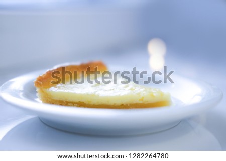 close up piece of lemon tart sprinkled with sugar powder and served on white plate