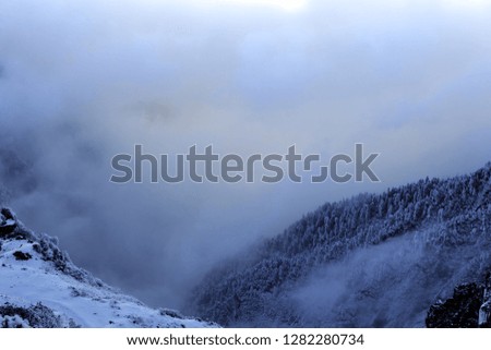 Abstract landscape photograph, mountains shrouded in clouds. Fog floating between mountain peaks, Chinese mountains. Ridgeline, artistic landscape image. Clouds settled between mountains