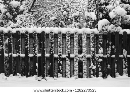wooden fence covered in snow in black and white