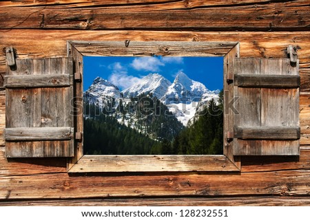 View through a wooden window on a mountain panorama with forest in foreground