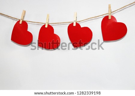Four red hearts on wooden pins on a white background