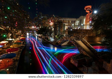 The River Walk in San Antonio, Texas is illuminated by colorful lights and animated by activity.