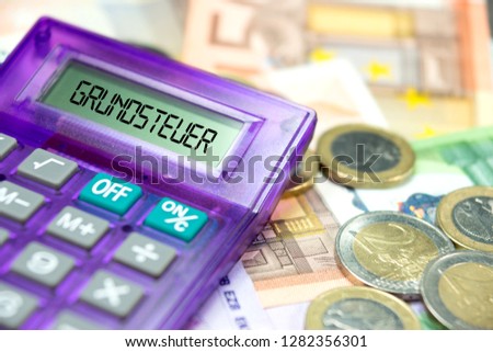Euro banknotes and coins, calculator and german word for property tax