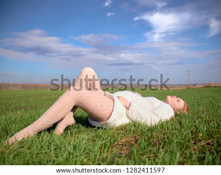 Beautiful pregnant woman in a white woolen sweater. Young beautiful pregnant woman on a green meadow.