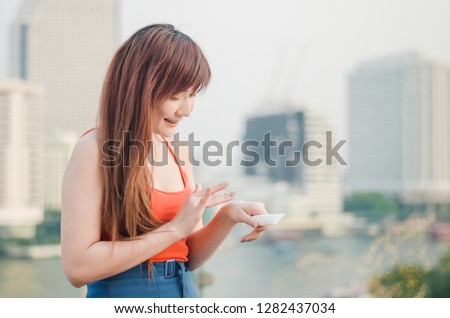 Young woman applying sunscreen lotion standing outdoors at the urban location during the sunny weather
