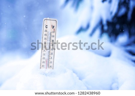 Winter time. thermometer on snow shows low temperatures