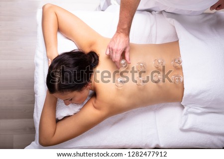 Relaxed Young Woman Receiving Cupping Treatment On Her Back In Spa Royalty-Free Stock Photo #1282477912