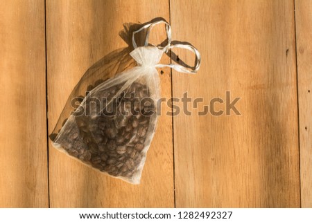 Coffee beans sourvenir in a small bag on wooden background, Wedding sourvenir concepts, Ribbon is a heart shape for valentine days