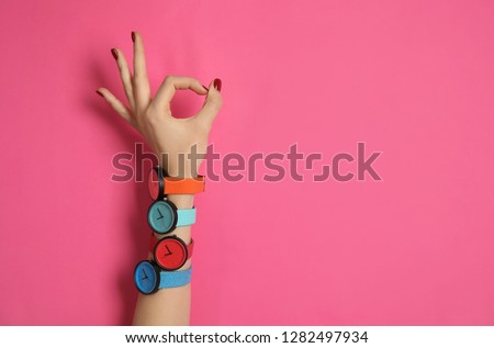 Woman wearing many bright wrist watches on color background, closeup view with space for text. Fashion accessory