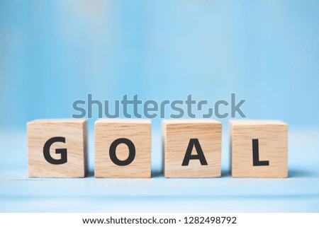 GOAL wooden cubes on blue table background with copy space for text. Business, Mission, Core Value and Solution concept