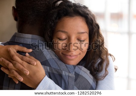 Happy african american wife hugging husband holding tight feeling grateful, smiling woman in love embracing beloved man, young black couple cuddling, support, sincere devotion and affection concept Royalty-Free Stock Photo #1282520296
