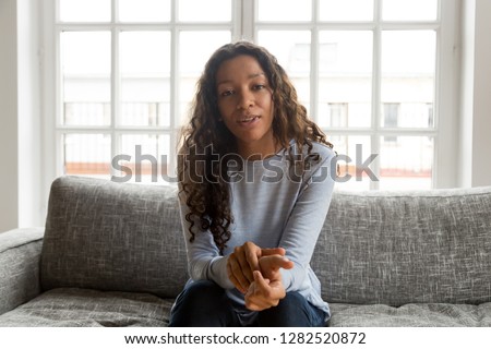 Serious friendly african woman internet teacher tutor looking at camera talking, black mixed race millennial female vlogger speaking making video call vlog, online job interview at home, portrait Royalty-Free Stock Photo #1282520872