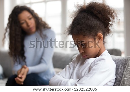 Mom or psychologist talking counseling upset offended african american child girl feels sad insulted, sulky frustrated black mixed race kid daughter having psychological trauma depression problem Royalty-Free Stock Photo #1282522006