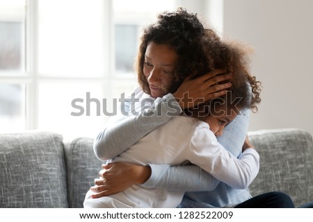 Loving single black mother hugging african daughter caressing cuddling, caring mom embracing supporting girl, mum and kid sincere warm relationships, foster care, child custody, adoption concept Royalty-Free Stock Photo #1282522009