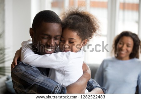 Cute little black girl embracing happy african american dad at home, mixed race kid daughter and father hugging cuddling, daddy and child love care connection good relations concept, family reunion Royalty-Free Stock Photo #1282522483