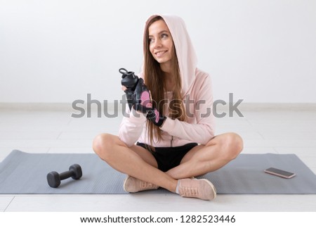 Healthy lifestyle, people and sport concept - Smiling woman sitting on yoga mat and drinking water after hard workout