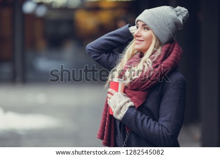 Close-up portrait of young blonde woman drinking coffe and enjoying the morning on the street. 